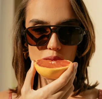Woman with sunglasses eating fruit